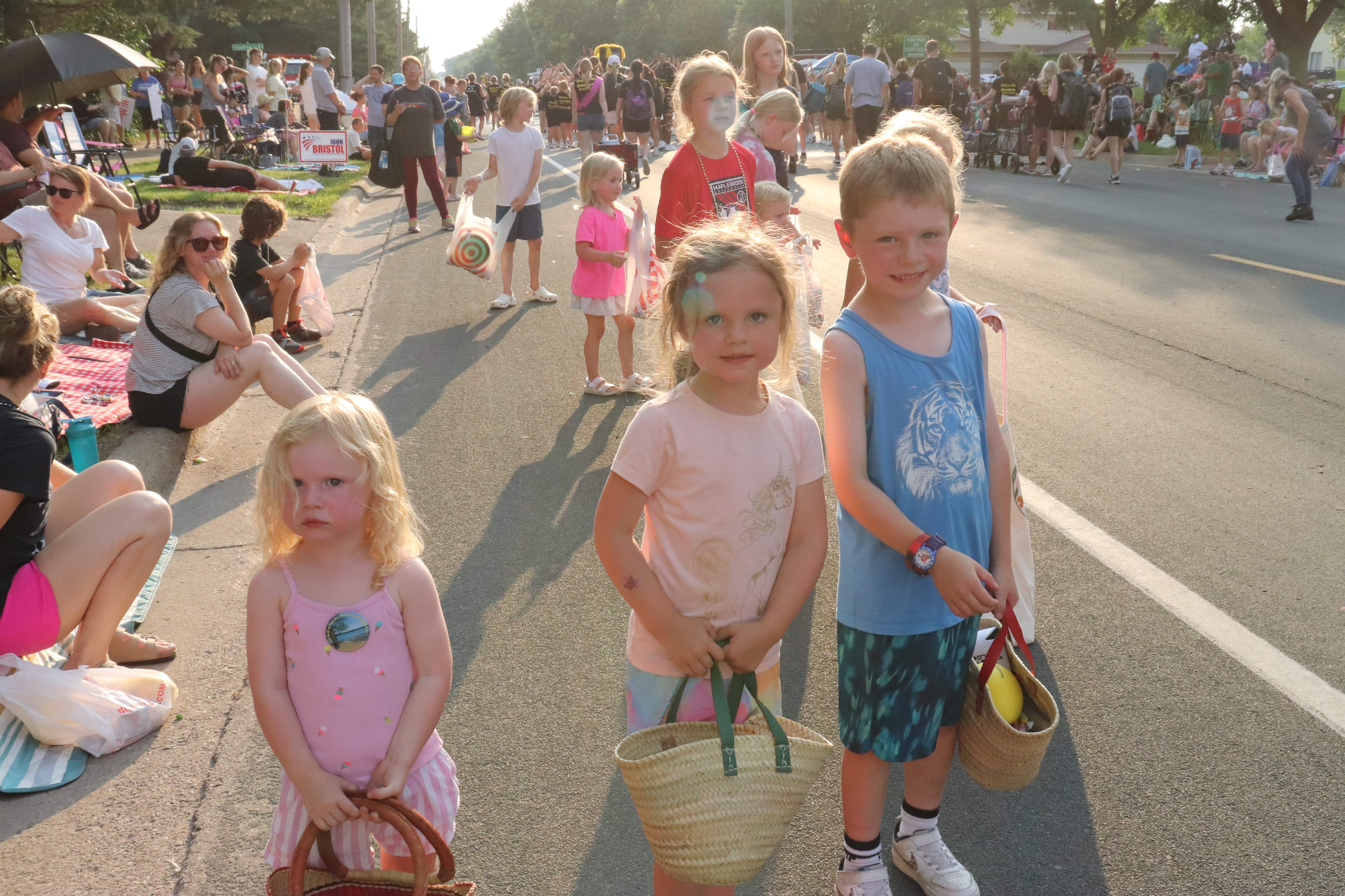 three children standing along parade route