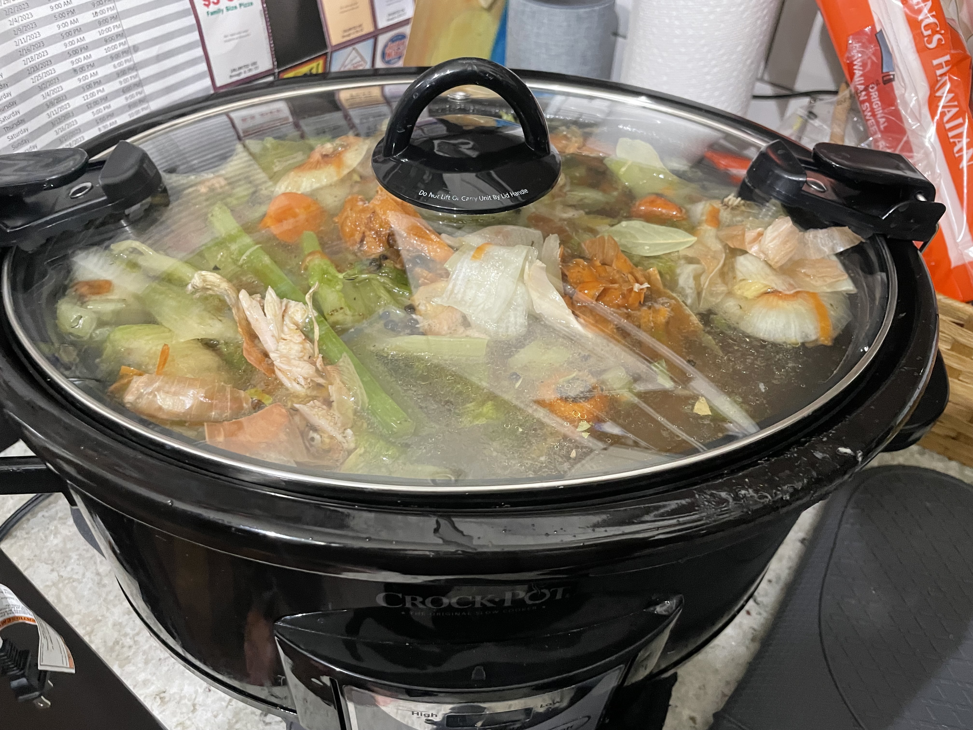 Crockpot with vegetables, chicken bones, seasoning, water.