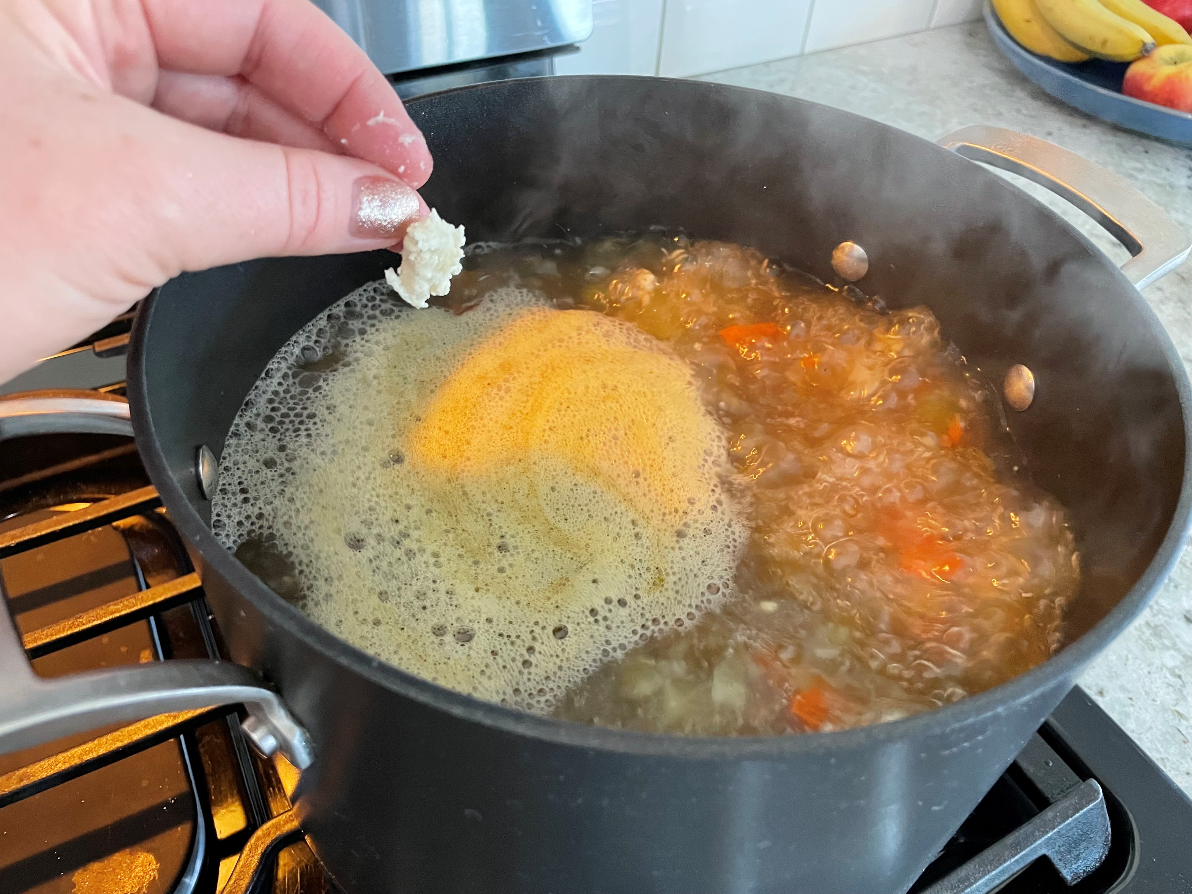 marble sized dough ball pinched in fingers over boiling soup